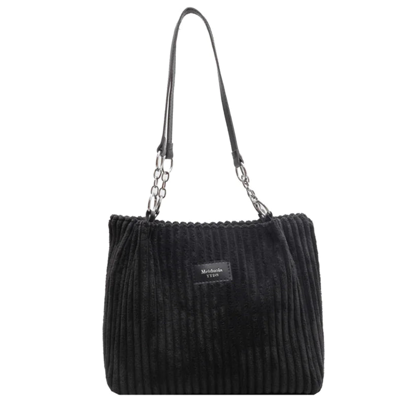 Black corduroy shoulder tote bag with soft ribbed fabric and chain-accented straps, designed for stylish and functional daily use.