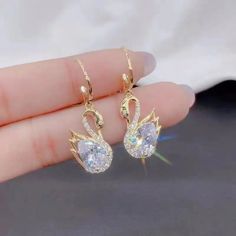Gold swan zirconium earrings with teardrop crystals and crystal accents.