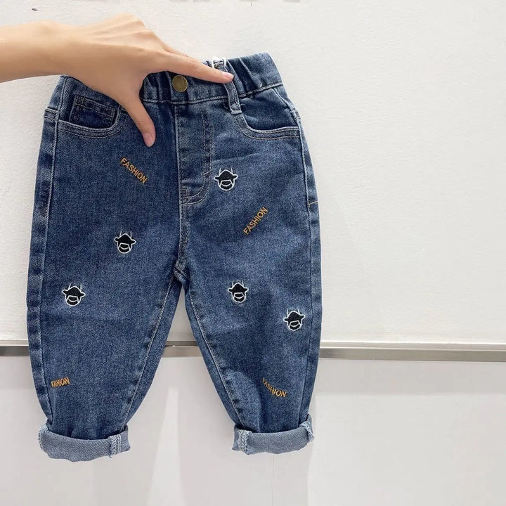 Blue denim casual all-match long pants for kids with cartoon face and 'FASHION' embroidery, ideal for everyday wear and comfort.