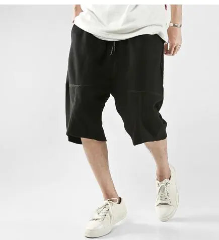 Black Hip-Hop Sports Shorts for Men in a loose harem fit, styled with white low-top sneakers for a streetwear look.