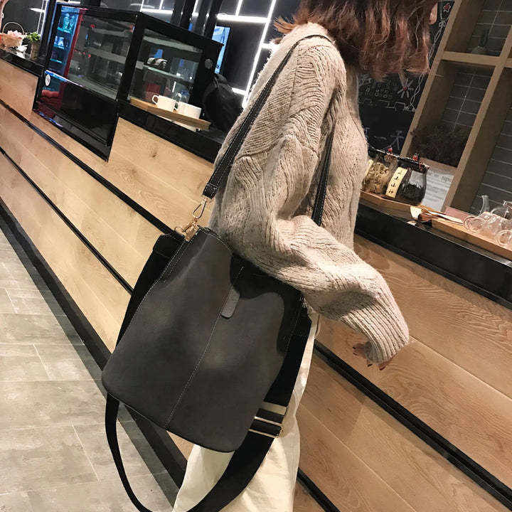Blake Shoulder Bag -Black styled with a casual outfit, showcasing its bucket design and wide strap for everyday use.